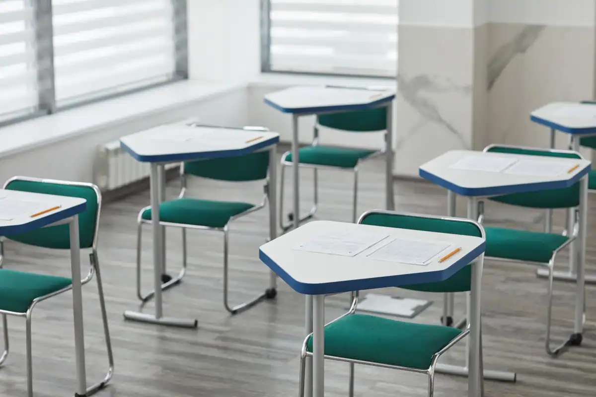 Sală de examen goală, cu bănci pregătite și foi de concurs pentru bacalaureat