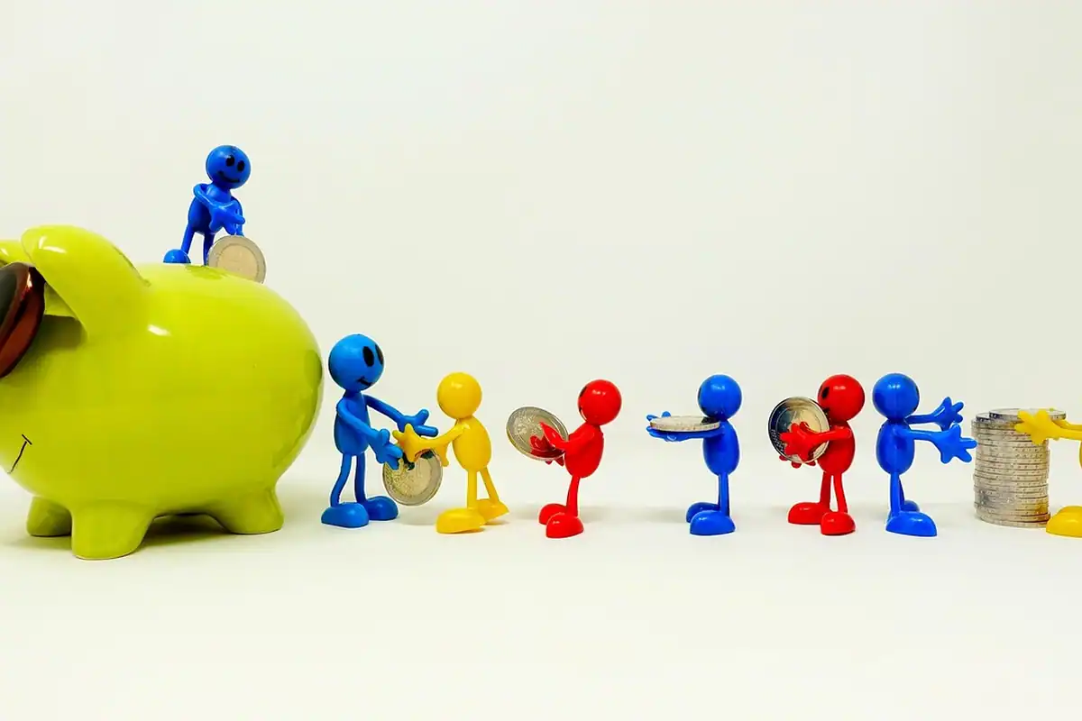 Pușculiță verde și figurine colorate care adună monede, simbolul economisirii unei burse