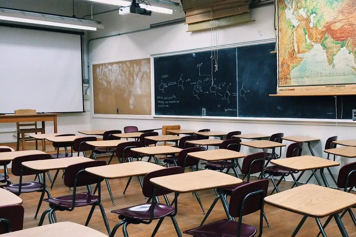 Sală de clasă cu bănci și o tablă, pregătită pentru ore