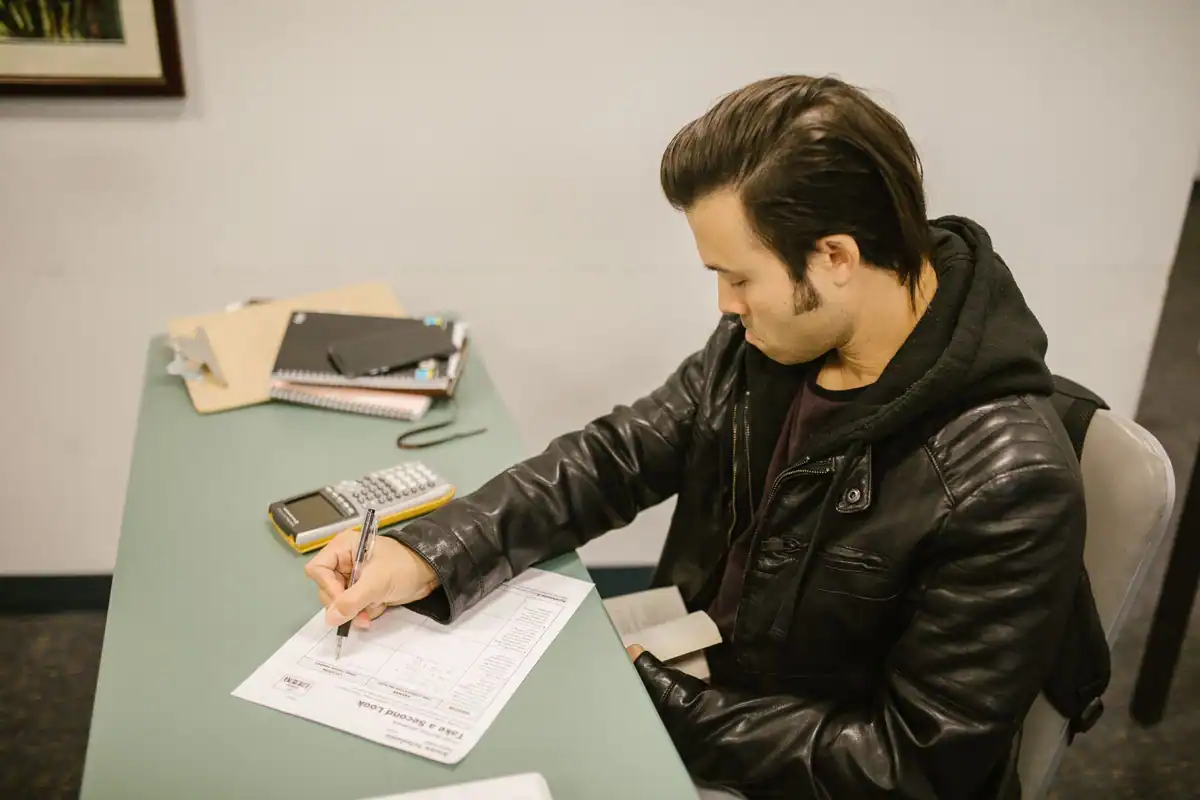 Student care rezolvă o lucrare scrisă în banca unei săli de curs