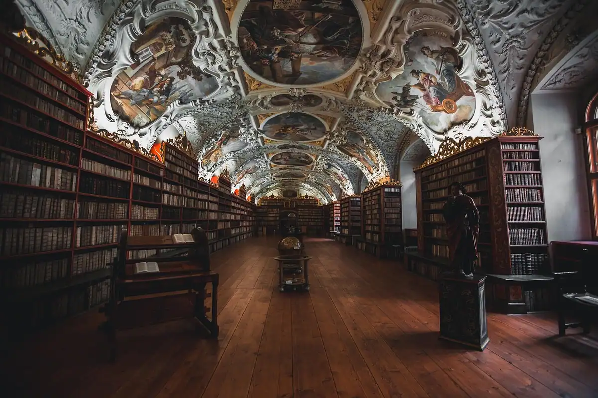 Bibliotecă mare cu rafturi pline de cărți și arcade în fundal