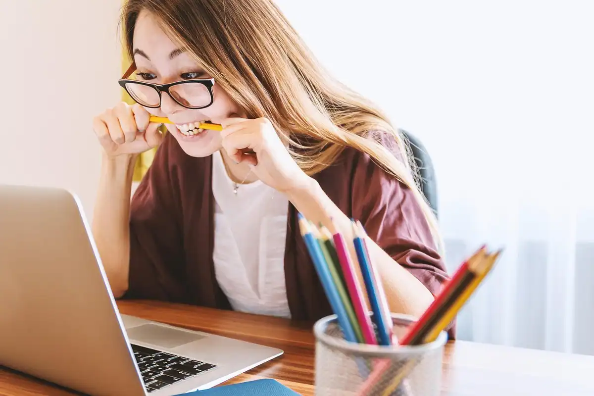 Tânără cu ochelari care caută ideile pentru eseu în fața laptopului