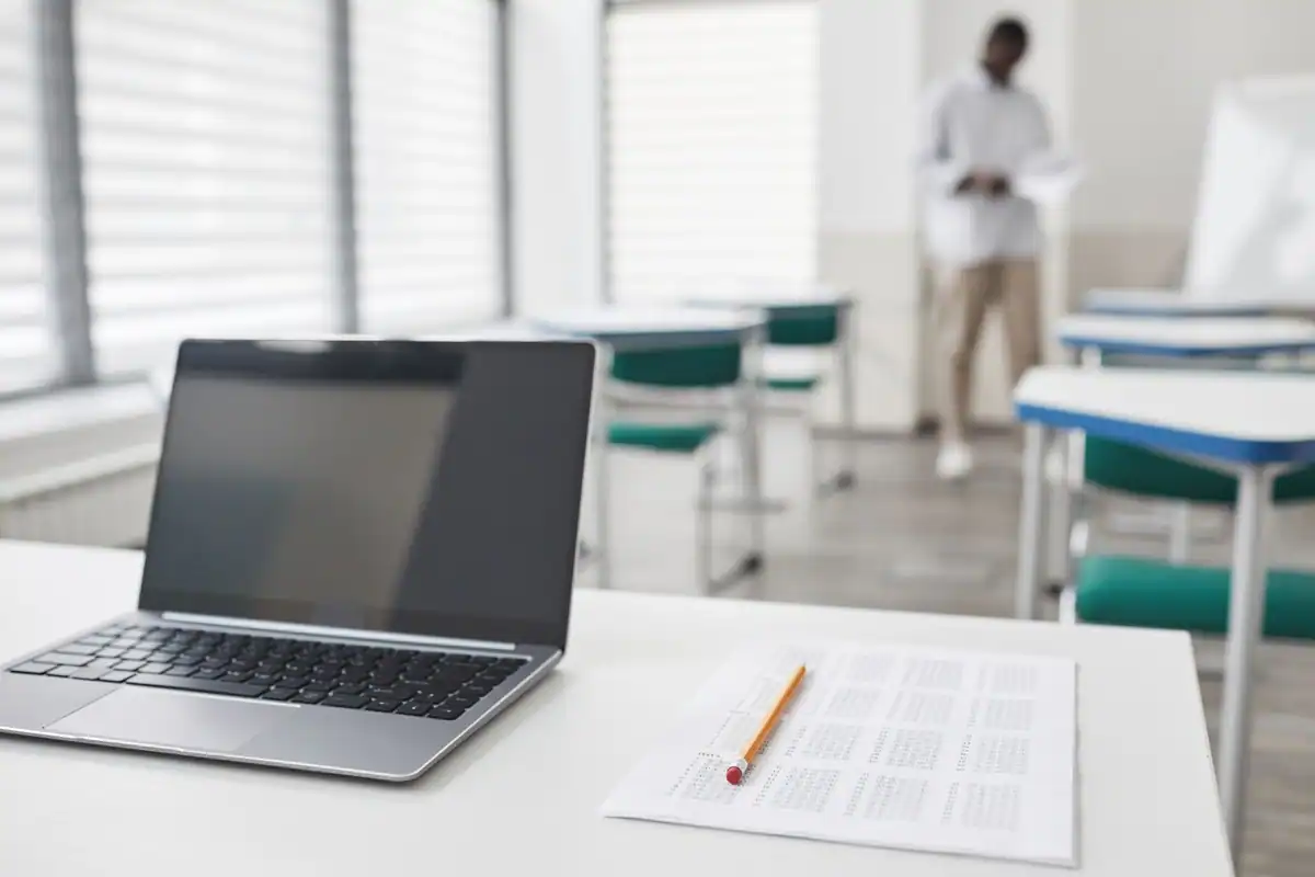 Laptop și foaie de evaluare pe o bancă dintr-o sală de clasă modernă