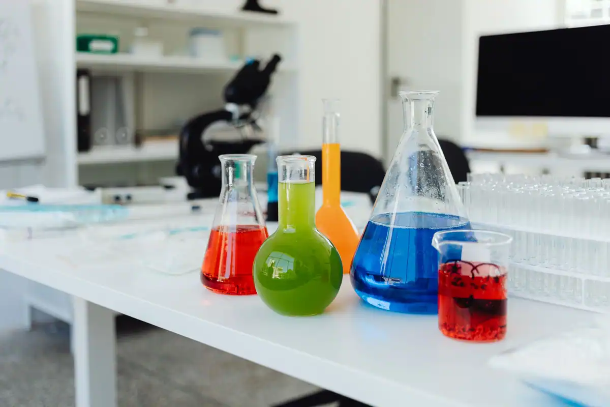 Eprubete și baloane cu soluții colorate pe masa laboratorului de chimie