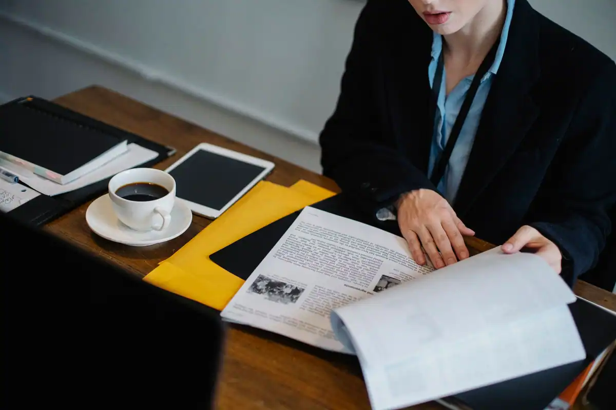 Persoană care verifică actele de studii la birou, lângă o ceașcă de cafea
