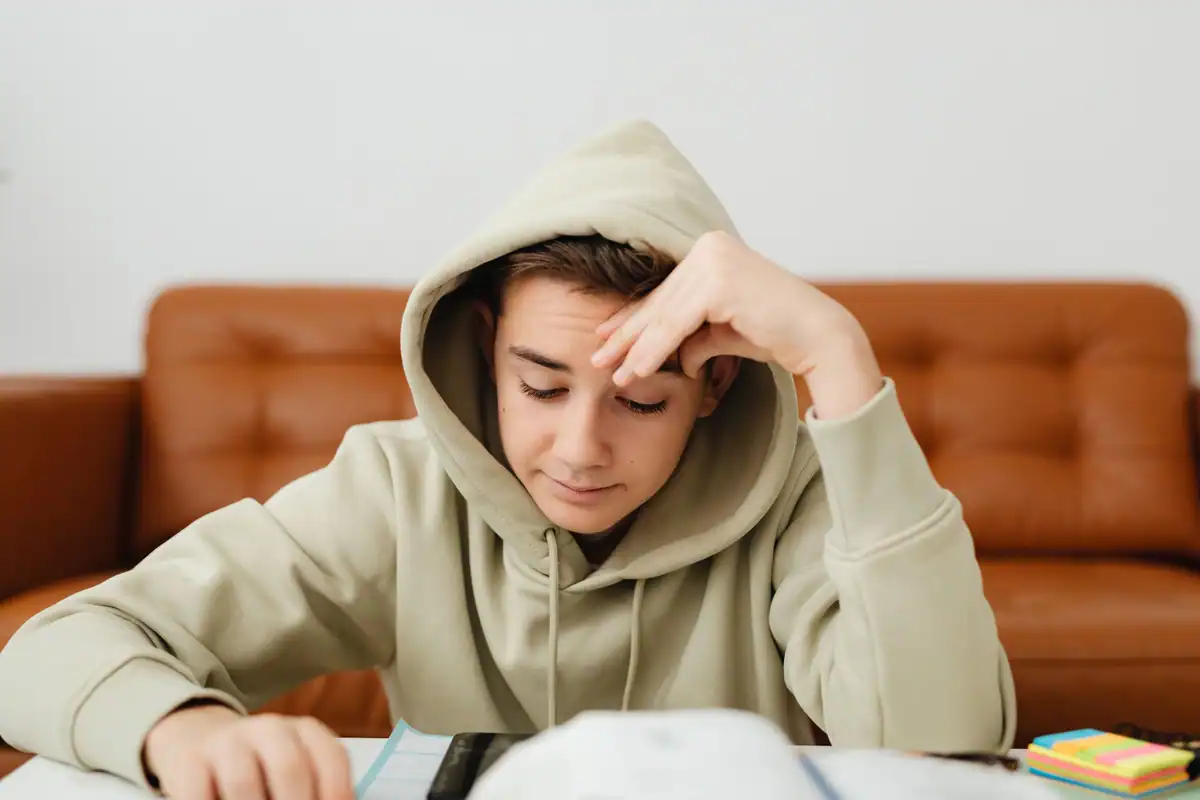 Adolescent cu glugă concentrat asupra temelor, în timpul unei sesiuni de studiu