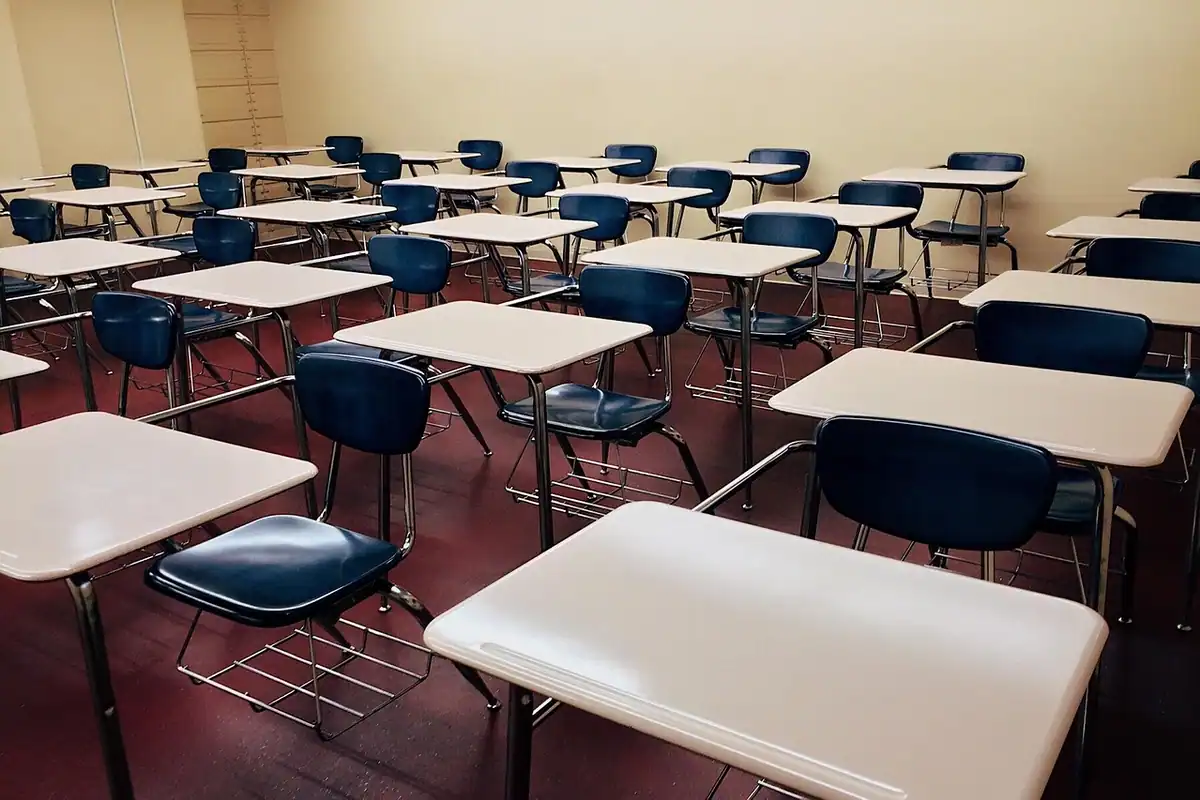 Sală de clasă goală, cu bănci din lemn aliniate în rânduri